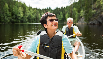 Image of a man and a woman kayaking while smiling.